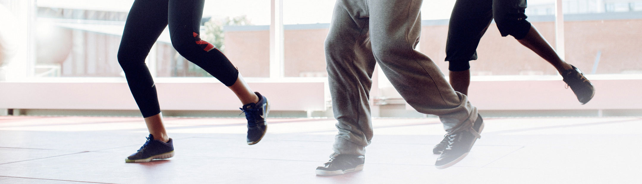 Halvbild på tre personer ben när de dansar i en ljus träningssal