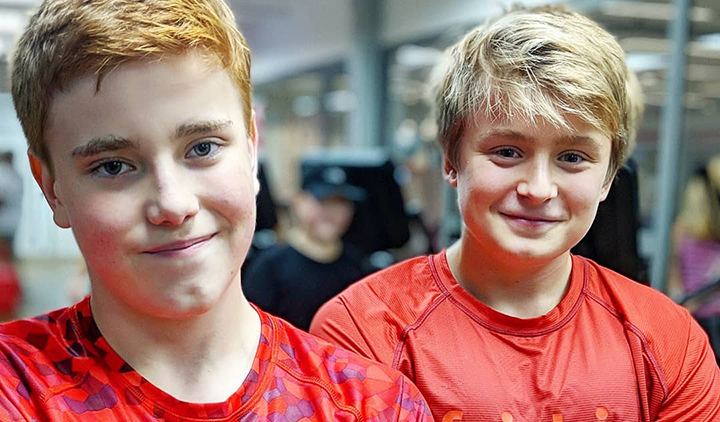 Två tonåringar med röda Friskiströjor står i gymmet.